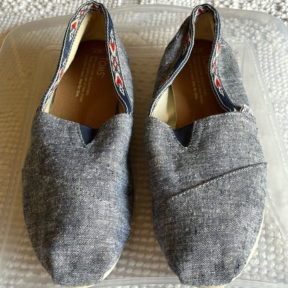 Toms denim look slip ons with navy blue and orange Aztec trim. Size 7